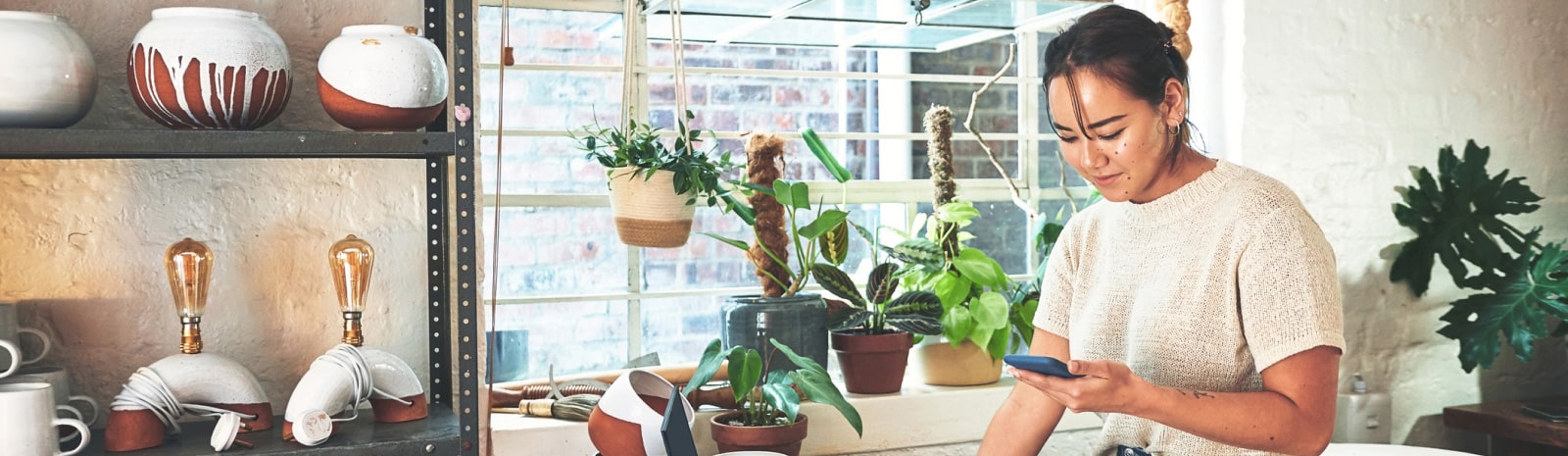 woman using phone in front of plants